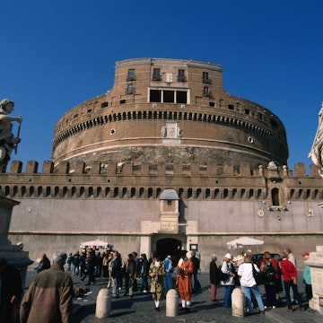 Tourists on the Pont Sant'Angelo make their way past the angels by Bernini and his pupils through to the heavily fortified Castel Sant'Angelo, Rome.