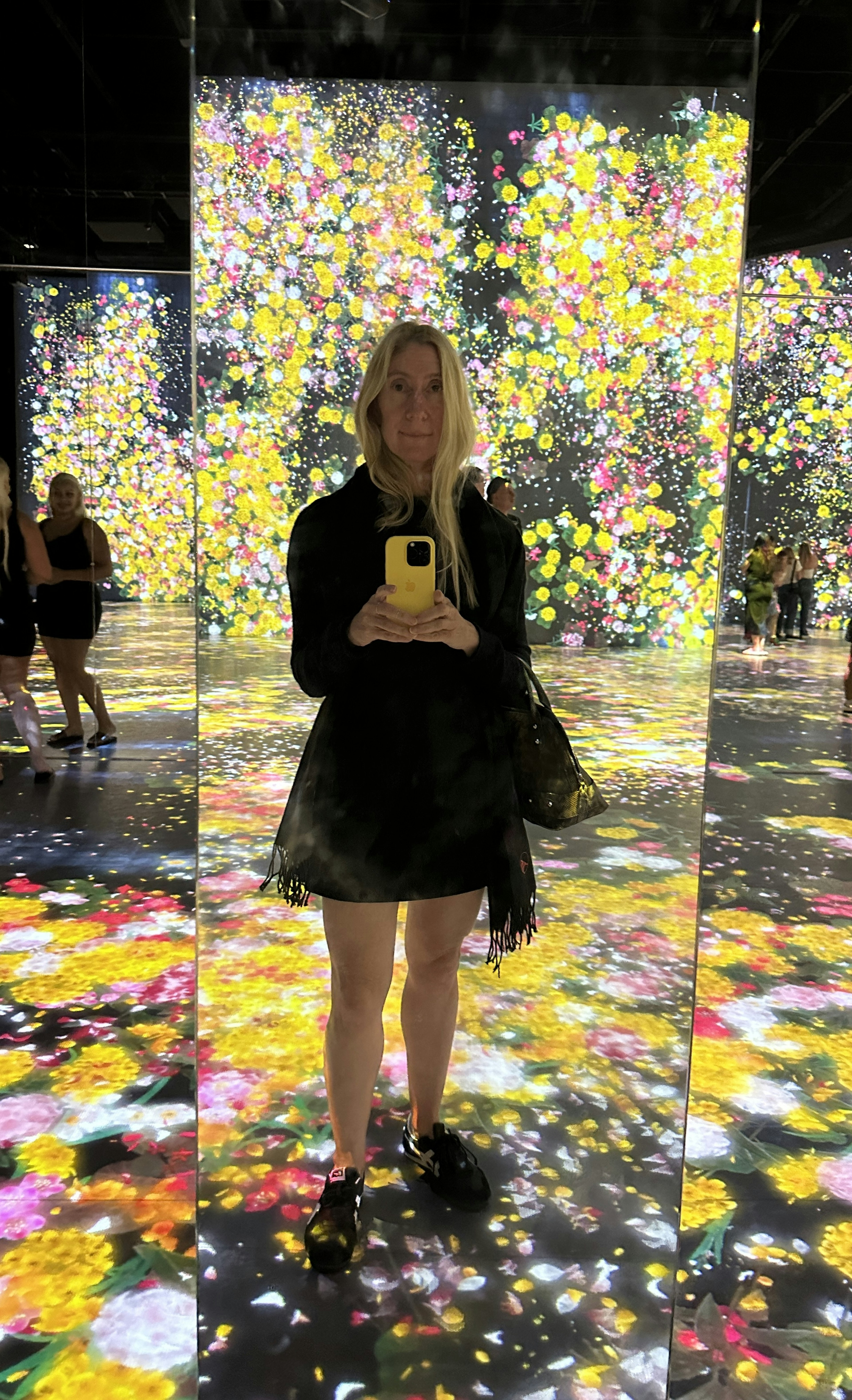 Caroline, the writer, takes a photo in an immersive exhibit where she is surrounded by images of flowers