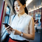 Beautiful young lady text messaging on smartphone while riding on subway MTR train