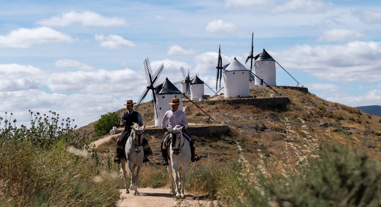 May 16, 2024: We started the day at the Centro Ecuestre Los Caireles.  There we met our hosts Miguel Angel and his brother Jesus, who own and run the farm.  (Miguel Angel wore a black vest.)  The Centro is a horse back riding school.  We shot pics at their farm and then headed to the town of Consuegra.  On the mountain overlooking the town, there is a castle and several windmills.  We shot pics and video of Miguel Angel and Jesus riding around the windmills and the castle.  This area is notable because it is where the fictional Don Quixote rode around in Miguel de Cervantes’ famous novel.  Afterward, we returned back to El Centro where we filmed our hosts riding by grape vineyards and olive groves to the nearby Villafranca de los Caballeros lagoons.
Spain Marketing 1379722