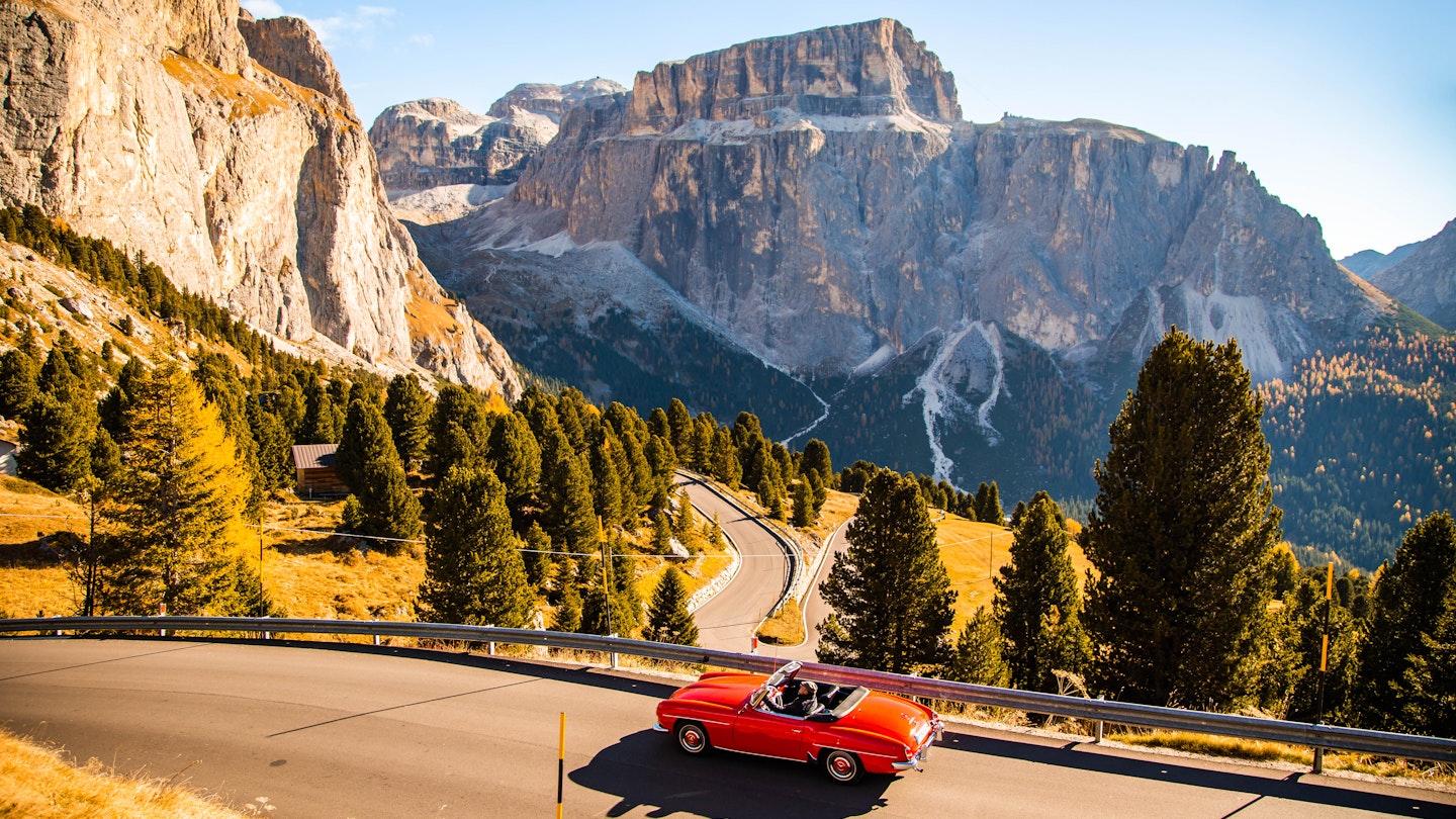 Driving with red convertible car in the Dolomites mountains during autumn season
1061872058