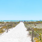 Bowman's beach at Sanibel Island with sandy trail, path, walkway, fence, many people, crowd in distance, crowded coast, coastline shelling, looking for shells
1163242073