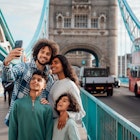 Multiracial family stand together on a bridge taking a selfie.
1680154341