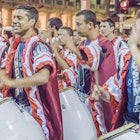 MONTEVIDEO, URUGUAY, JANUARY - 2016 - Costumed men drummers playing traditional music called candombe at the inaugural parade of carnival of Montevideo, Uruguay
509477210
Holiday, Group Of People, Montevideo, Stage Make-up, Celebration, Latin Music, Musical Band, Music, Traditional Clothing, Latin American Culture, Latin American and Hispanic Ethnicity, Period Costume, Multi Colored, Cultures, National Landmark, Entertainment, Travel Destinations, Human Face, Traditional Musician, People, Uruguay, South America, Drum, Percussion Instrument, Carnival, Party - Social Event, Traditional Festival, Event, Costume, Stage Costume, costumed, Touristic Attraction, Candombe, Drummer, Traditional Music
Costumed men drummers playing traditional music called candombe at the inagural parade of carnival of Montevideo, Uruguay