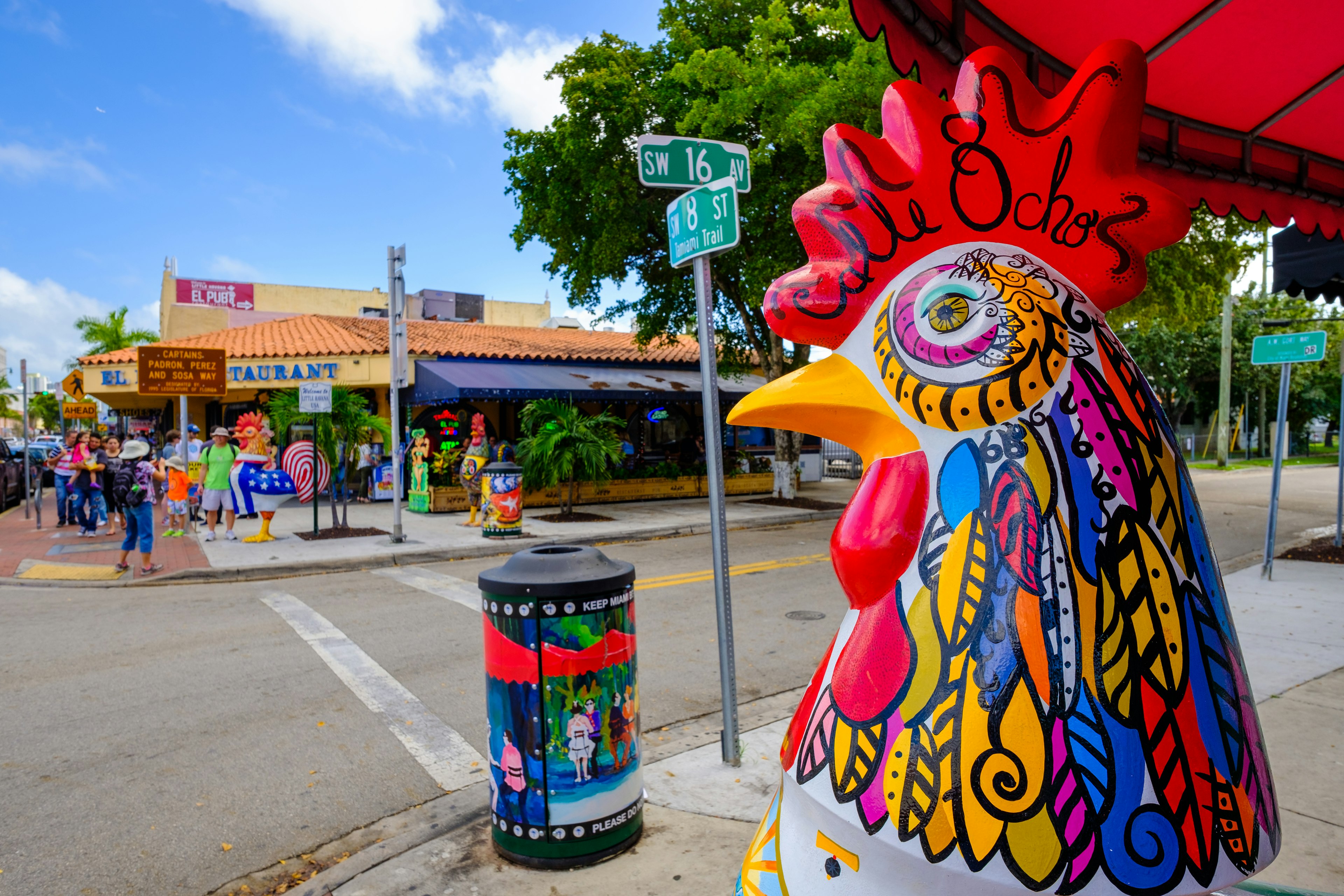 Street art and a mural-covered cockeral sculpture on a sunny day