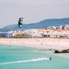 Kite surfing in Tarifa with beachgoers on the sand.
