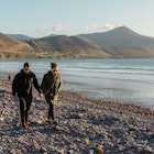 Ireland coastline with view of the ocean and mountains, man and woman walking through Ireland wind
Ireland coastline with view of the ocean and mountains, man and woman walking through Ireland wind