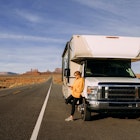 A woman travels by motorhome through Monument Valley in the USA desert and checks her mobile phone parked on the side of the road; Shutterstock ID 1664258755; your: Brian Healy; gl: 65050; netsuite: Lonely Planet Online Editorial; full: Best road trips in Utah